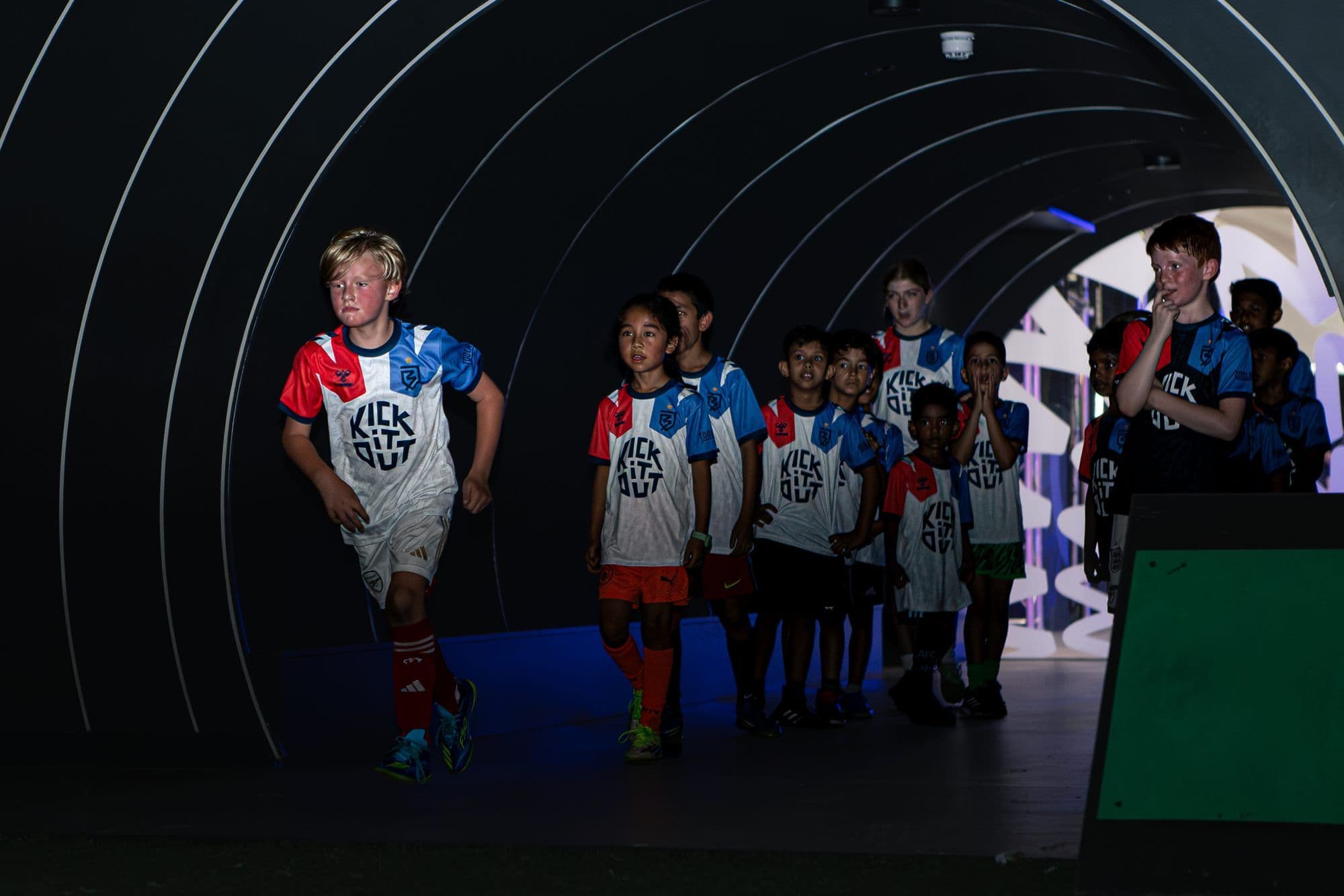Children walking out through the lit player tunnel